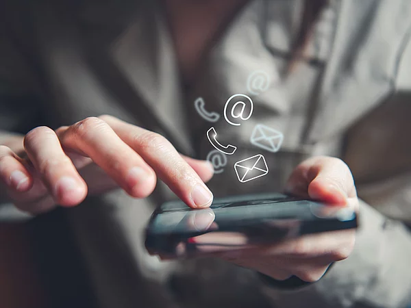 Mann hält ein Smartfon fest auf dem Social-Icons erscheinen
